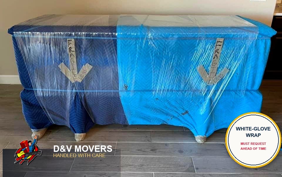 A dresser fully wrapped in moving blankets and shrink wrap with fragile labels